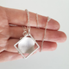 Handmade silver square pendant (back font) is shown on the palm.