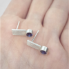 Silver stud earrings with cubic zirconia are shown on the palm.
