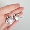 Minimalist square silver drop earrings on the palm