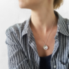 Contemporary Handmade Custom Silver 3 CZ Circle Pendant Necklace is worn on the woman in a striped shirt.