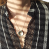 Silver minimalist doughnut pendant is worn on a white lady in a striped shirt.