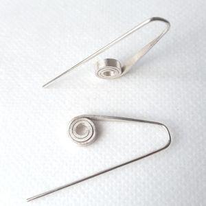 Handmade Silver spiral earrings are shown on a white surface.