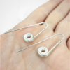 Long Silver threader earrings are displayed on the palm.