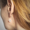 Silver minimalist threader earrings are worn on a white lady.
