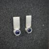 Sterling silver minimalist earrings are shown on the black sponge.