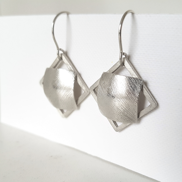 Statement silver dangle earrings hanging on the stand