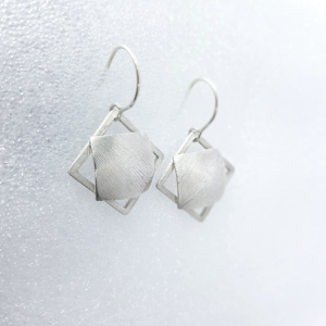 Statement silver dangle earrings handing on the stand