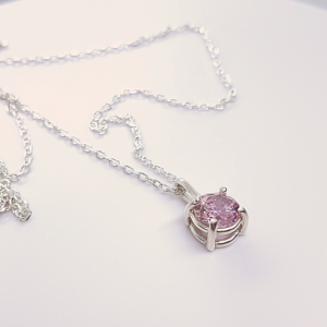 Hand-carved personalised CZ Solitaire Pendant Necklace is placed on the white surface.