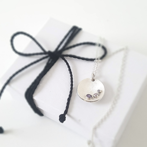 Silver 3 CZ Circle Pendant Necklace is placed on the white paper gift box tied with black cotton string.