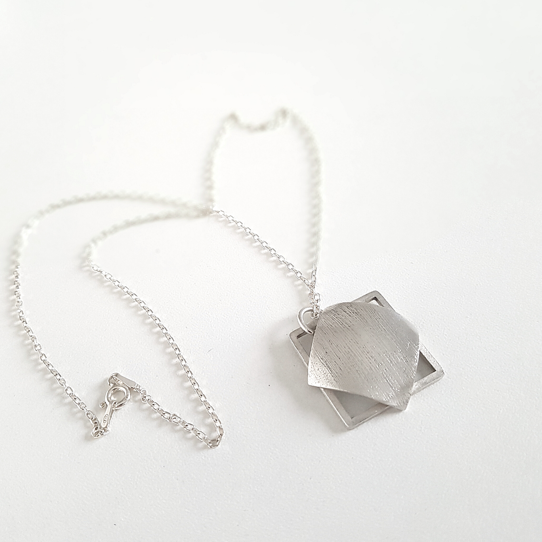 Geometric pendant is shown on the white surface.
