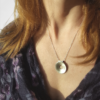 Silver minimalist circle pendant necklace is worn on a white lady.