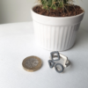 Artisan Geometric Patina Statement Ring in Sterling Silver is displayed on the white surface near the British sterling pound and a cactus.