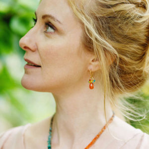 Woman wearing colourful orange gemstone earrings.
