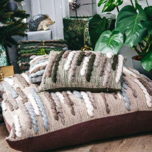 Cassandra Sabo’s handwoven Merino wool rectangular 'Caterpillar' cushion from her Forest Collection styled in front of the fireplace
