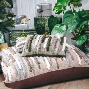 Cassandra Sabo’s handwoven Merino wool 'Caterpillar' floor cushion from her Forest Collection set in front of the fireplace