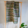 Handwoven 'Double Tendril' throw featuring Merino wool by Cassandra Sabo draped over a hanging rail