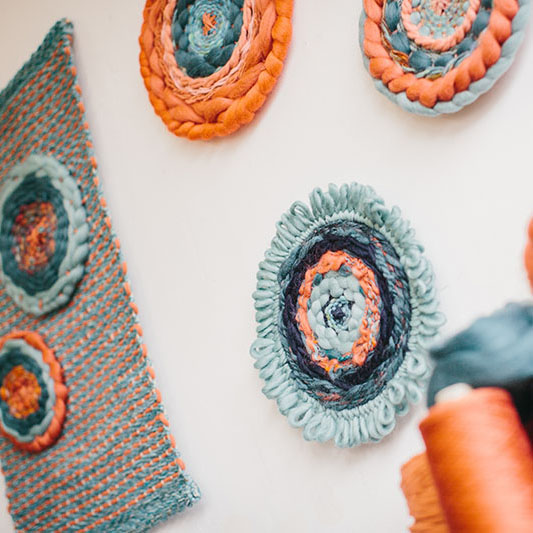 Cassandra Sabo’s ‘West Coast 1’ woven circular textile wall-hanging from her West Coast Collection hung on the wall with multiple artworks from this collection