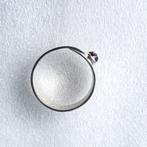 Statement Overlap minimalist silver ring with amethyst is placed on the white surface.
