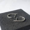 J shaped stud earrings in sterling silver are placed on a black sponge.