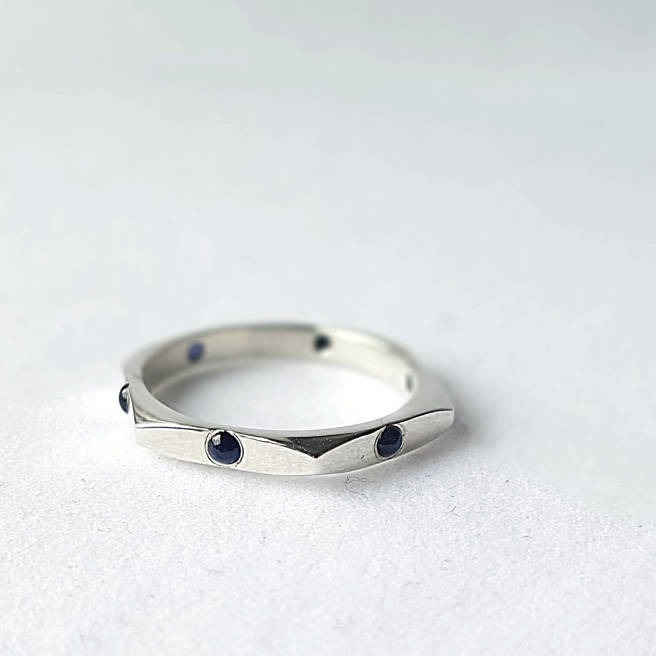 Sterling silver ring with six Cabochon Sapphires is placed on the white surface.