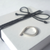 Open Sterling silver ring with one gemstone is placed on the white gift box tied with black cotton string.