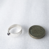 Sterling silver ring with Cabochon Amethyst is placed next to one pound on the white surface.
