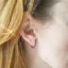 Handcrafted Sterling silver earrings are worn on the earlobe of the white woman.