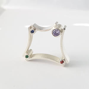 Minimalist silver ring with cubic zirconias stands on a white surface.
