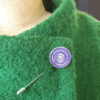 Purple aluminium women's suffrage pin displayed on lapel of coat