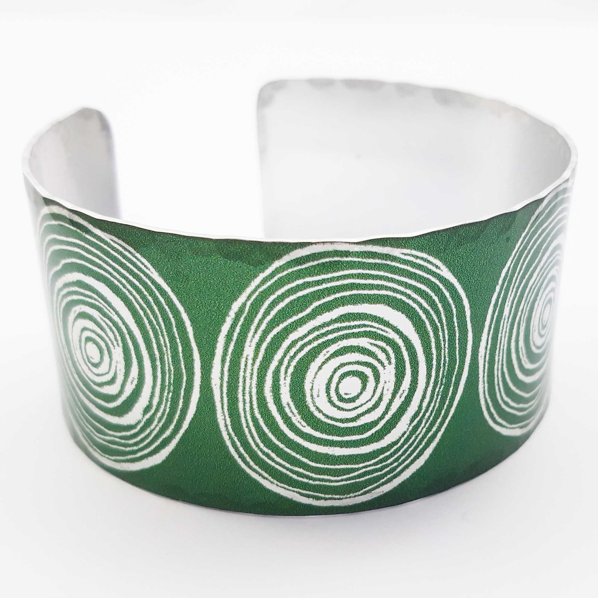 Front view of green women's suffrage bangle with large scroll motifs in a silvery colour