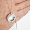 Circle pendant with three gemstones is shown on the palm.