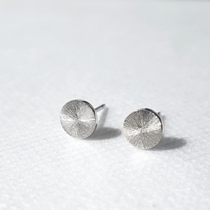 Circle silver earrings with a sun rays texture and mirror polish on a white background.