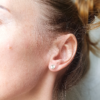 Handcrafted Geometric Silver stud earrings on an earlobe.