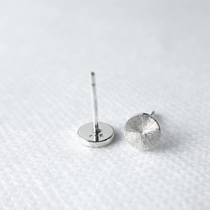 Statement Silver stud earrings with a sun rays texture and mirror polish on a white background.