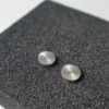 Silver stud earrings (front view) with a sun rays texture on a black sponge block