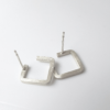 Square silver wire earrings on a white surface.
