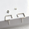 Contemporary square silver stud earrings on a white box.