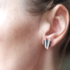Contemporary handcrafted silver stud earrings on an earlobe.