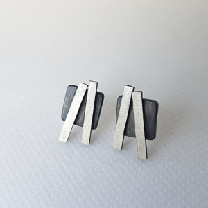 Contemporary artisan custom silver stud earrings on a white surface.