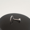 Handcrafted nose piercing stud on a black surface.
