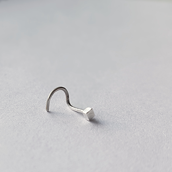 Handmade nose piercing stud on a white surface.