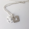 Custom initial letter and flower pendant necklace on a white surface.