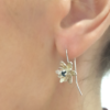 Designer silver earrings with topaz on a the earlobe.