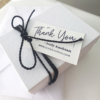A white gift box tied with black cotton string and Thank you card.