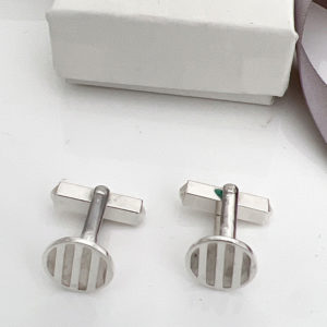 Striped silver cufflinks near a jewellery box