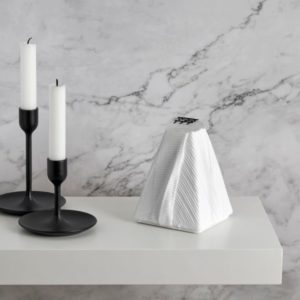 White glass pyramid sculpture with ribbed texture in an interior setting