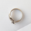 Contemporary flower and butterfly ring in silver and gold on a white surface.