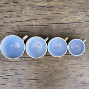 Four cappuccino cups seen from the top down to illustrate the size range available, glazed in pale speckled blue.