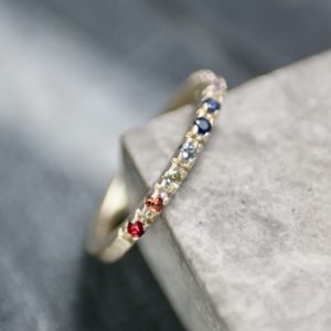 Rainbow sapphire ring resting on edge of marble tile.