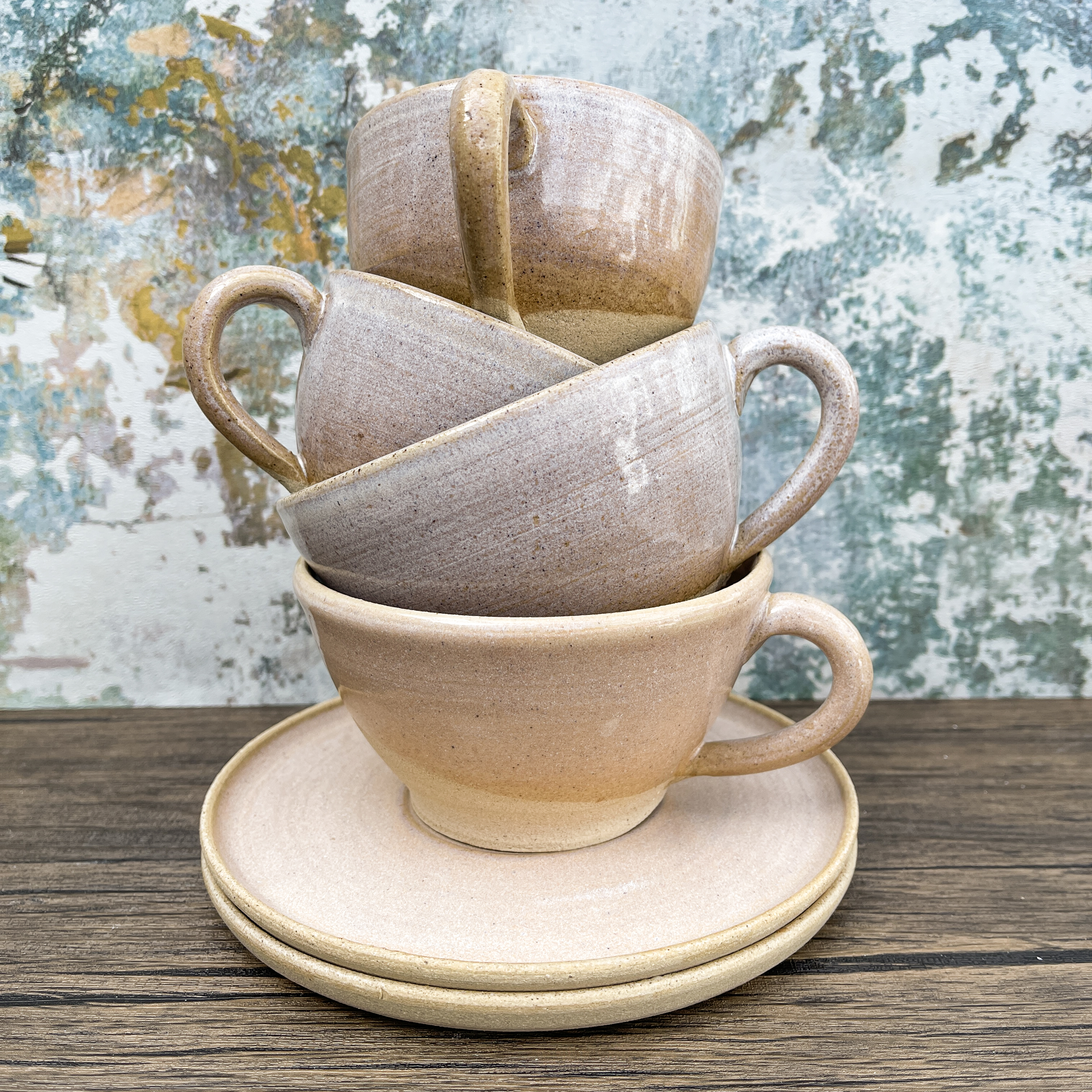 Three cappuccino cups stacked inside each other on a wooden tabletop